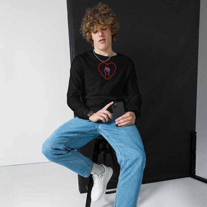 Person wearing a black sweatshirt with a red heart design and pink solidarity fist, sitting on a chair against a black backdrop.