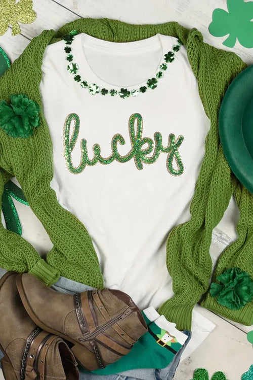Baby onesie with 'lucky' text and green shamrock design, wrapped in a green blanket with shamrock patterns.