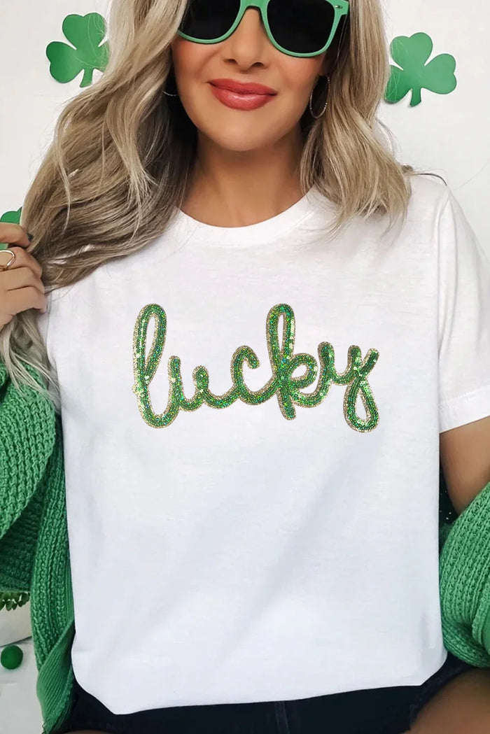 Person wearing a white t-shirt with 'lucky' in green sequins, surrounded by shamrock decorations.