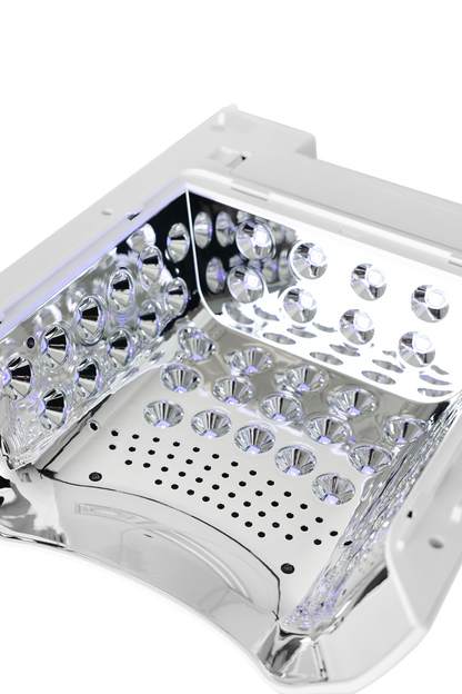 Close-up of a white and silver LED light therapy panel showing the interior with multiple clear faceted crystal prisms and a perforated metal plate.