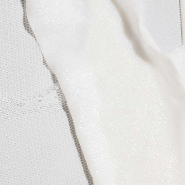 Close-up of a white sheet mask with a dotted texture on a textured fabric background