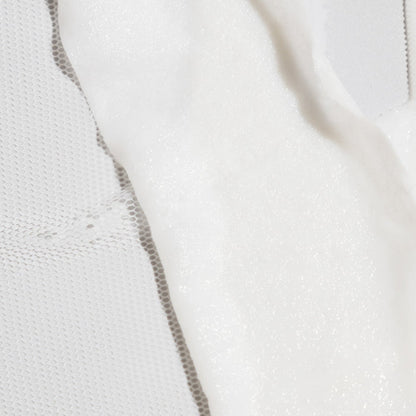 Close-up of a white sheet mask with a dotted texture on a textured fabric background