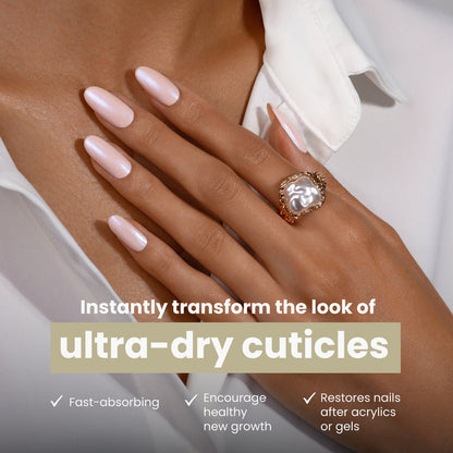 A hand with manicured, light pink nails and a large ring rests on a white shirt. Text promotes LONDONTOWN’s Mini Nourishing Cuticle Oil—a fast-absorbing essential for ultra-dry cuticles and nail restoration, perfect for travel.