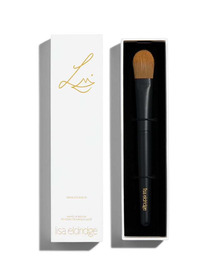 handle and a flat rounded brush. The lid of the box sits next to the bottom and has the Lisa Eldridge logo in gold as well as the text, ‘SEAMLESS BLEND MAKE UP BRUSH PINCEAU DE MAQUILLAGE lisa eldridge’