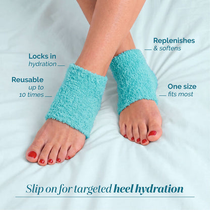 A pair of feet wearing LONDONTOWN Pedi Perfect Heel Socks in turquoise, shown on a bed. These fluffy, reusable socks lock in moisture for heel therapy, soften heels, and offer a comfortable one-size fit.