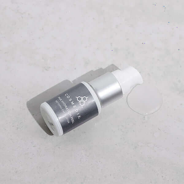 PHA Hydration Peel bottle lying on its side on a pale textured surface with a spill nearby