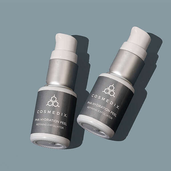 Two Cosmedix PHA Hydration Peel bottles with dark labels on a blue gray background