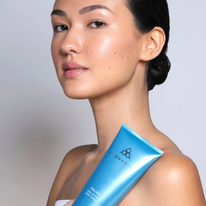 Profile view of a woman holding a blue Cosmedix Polish Dual-Action Body Scrub tube