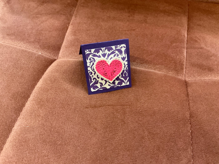 Colorful quilled heart pin from Cat's Quilling featuring intricate paper coil design on a metal pin back.