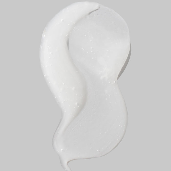 Close-up of a white creamy texture with tiny bubbles on a curved cosmetic surface
