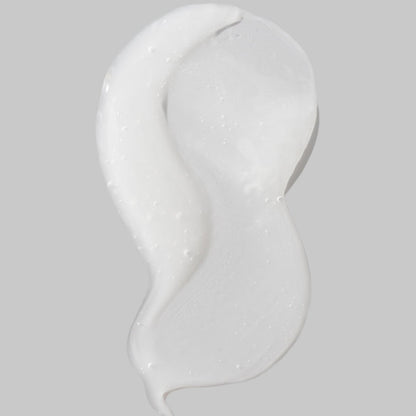 Close-up of a white creamy texture with tiny bubbles on a curved cosmetic surface