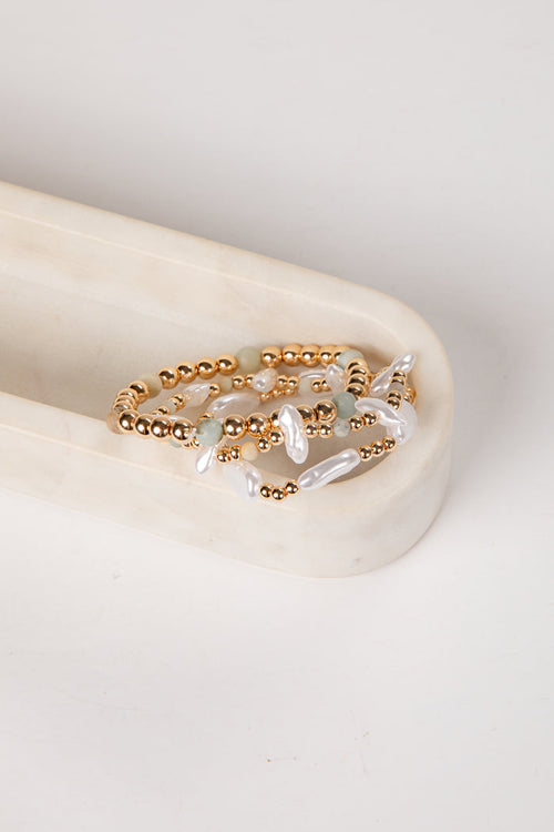 Gold and pearl beaded ring on a light stone surface