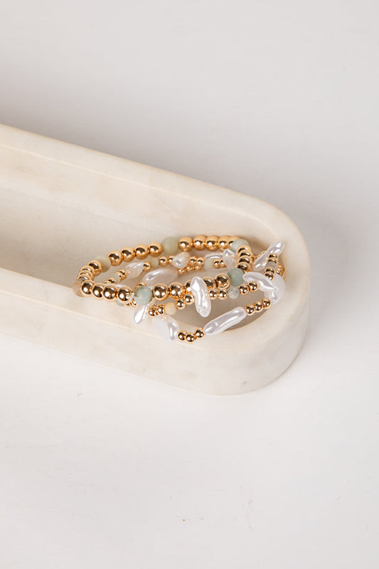 Gold and pearl beaded ring on a light stone surface