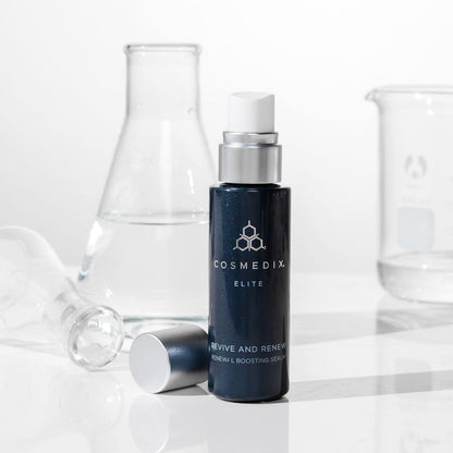 CosMedix Elite Renewal Boosting Serum bottle with dropper cap on a white surface, lab glassware in the background