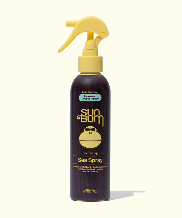 Sun Bum Sea Spray texturizing hair spray in a dark brown bottle with a yellow spray nozzle