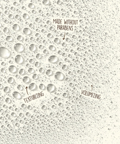 Close-up of clear water droplets on a light surface highlighting Sea Spray by Sun Bum’s volumizing and texturizing effect without parabens.