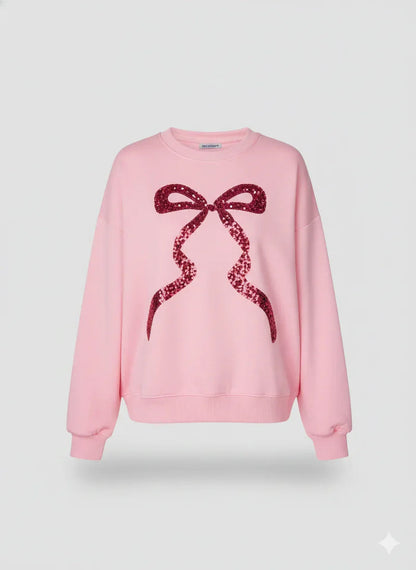 Pink sweatshirt with a red sequin bow design on a light gray background