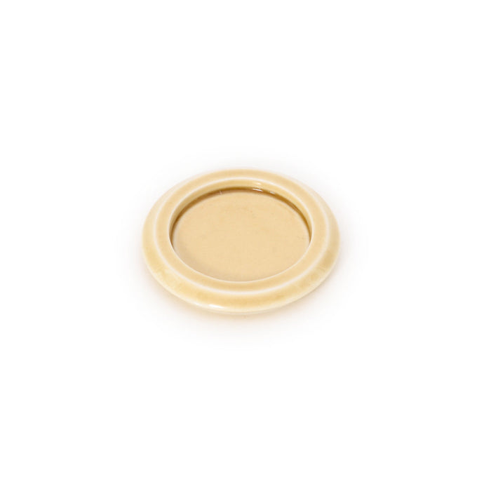 Cream-yellow ceramic incense tray with smooth round rim and centered dish