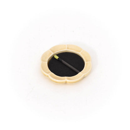 Cream-yellow ceramic incense tray with black incense pad and two incense sticks