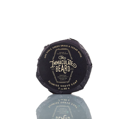 The Immaculate Beard shave soap puck in a round container, showing the smooth soap surface and brand label.