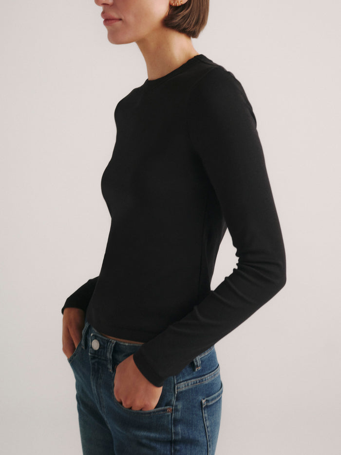 DL1961 Shrunken Tee long-sleeve in black, fitted crew-neck top with blue jeans, side profile.
