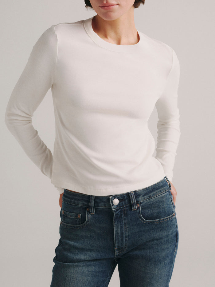DL1961 Shrunken Tee long-sleeve in white, a fitted crew-neck knit top, worn with blue jeans, front view.