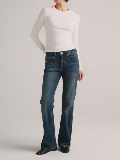 DL1961 Shrunken Tee long-sleeve in white with blue flared jeans, full-length front view.