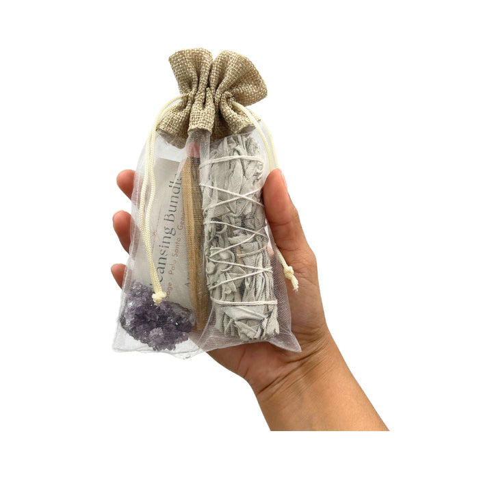 Hand holding a Smudge & Crystal Cleansing Bundle - Amethyst against a white background