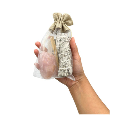 Hand holding a Smudge & Crystal Cleansing Bundle - Rose Quartz on a white background