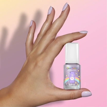 A hand with soothing lavender manicured nails holds a LONDONTOWN Sweet Dreams nail polish bottle, featuring a Care Bears design, against a pastel gradient background.